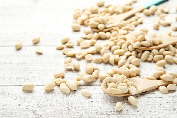 Kacang dengan sendok di meja kayu putih — Stok Foto