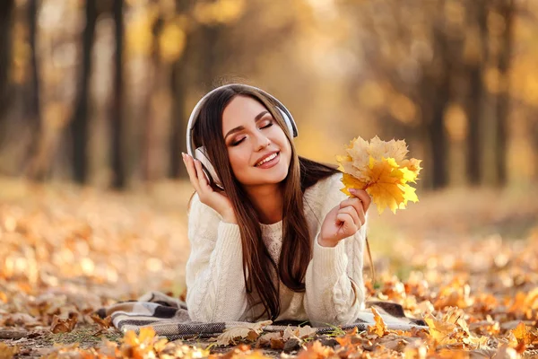 Mooie vrouw met koptelefoon en Maple Leafs liggend op de gro — Stockfoto