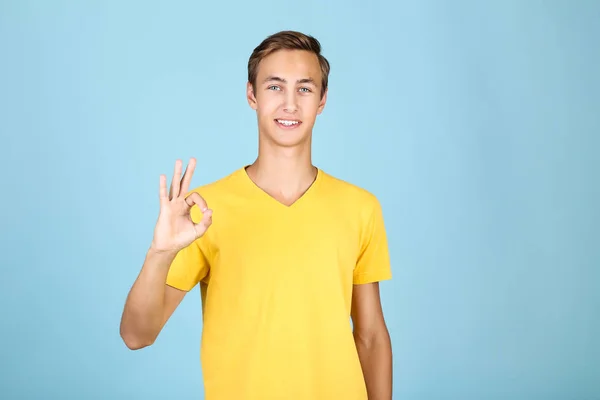 Porträtt av ung man i gul t-shirt på blå bakgrund — Stockfoto