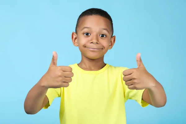 Schattige Amerikaanse jongen tonen duim omhoog op blauwe achtergrond — Stockfoto