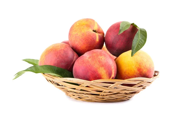 Fresh peaches with green leafs in basket isolated on white backg — Stock Photo, Image