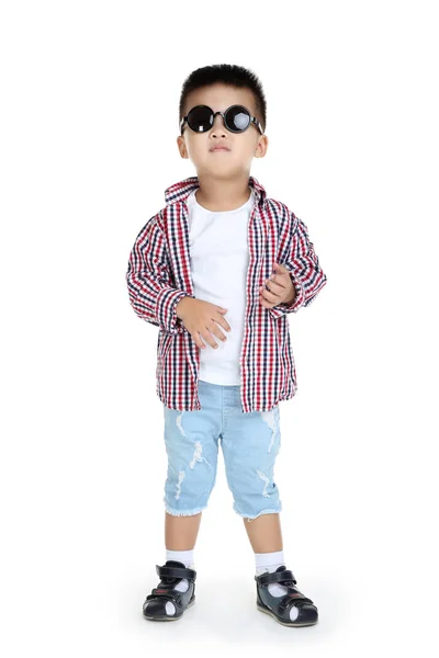 Vacker pojke i Modekläder och solglasögon på vit bakgr — Stockfoto