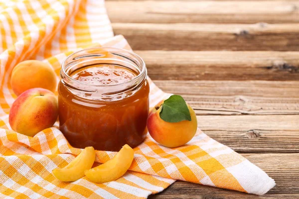 Marmelade im Glas und Aprikosen auf braunem Holztisch — Stockfoto