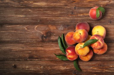 Kahverengi ahşap masa üzerinde yeşil yapraklı taze şeftali