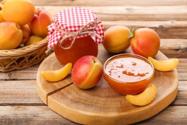 Kahverengi ahşap masa üzerinde kase ve kavanoz kayısı reçeli