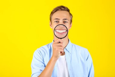 Sarı arka planda büyüteç ile genç adam