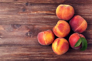 Kahverengi ahşap masa üzerinde yeşil yapraklı taze şeftali