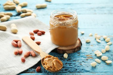 Mavi ahşap masada fıstık ezmesi ve fındık