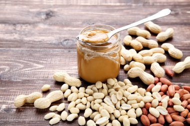 Kahverengi ahşap masada fıstık ezmesi ve fındık