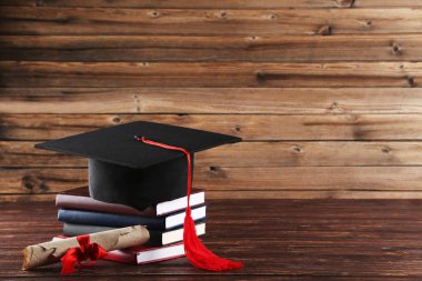 Diploma ve kahverengi ahşap t üzerinde kitap yığını ile mezuniyet kap