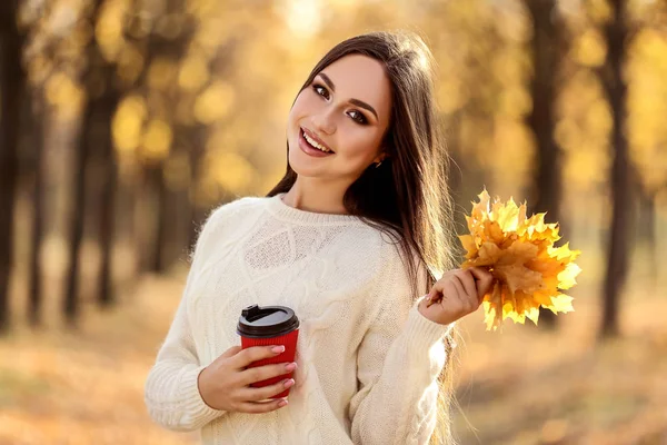 Mooie vrouw vasthouden Maple Leafs en papier Cup in herfst Park — Stockfoto