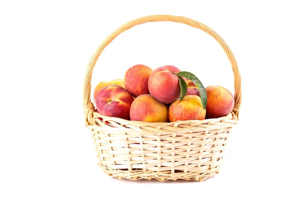 Fresh peaches with green leafs in basket isolated on white background — Stock Photo, Image