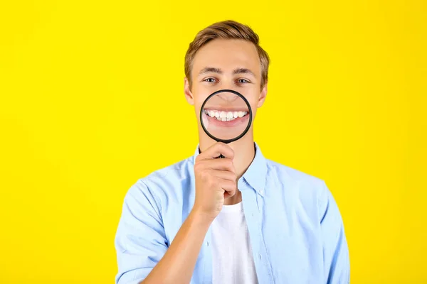 Ung man med förstoringsglas på gul bakgrund — Stockfoto