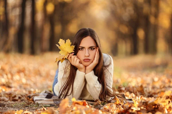 Mooie vrouw met Maple Leafs liggend op de grond in de herfst p — Stockfoto