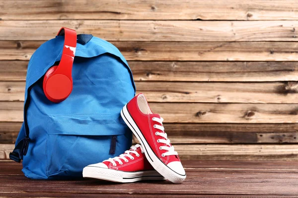 Sac à dos scolaire avec écouteurs et baskets sur onglet en bois marron — Photo