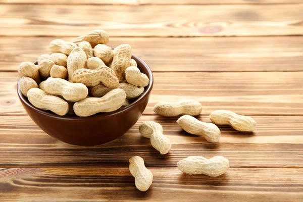 Erdnüsse in Schale auf braunem Holztisch — Stockfoto