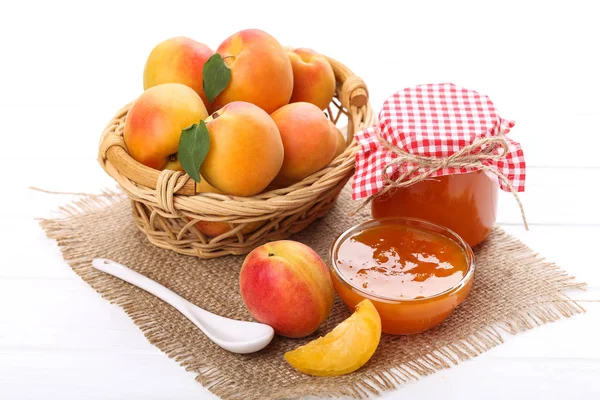 Jam in schaal en abrikozen op witte houten tafel — Stockfoto