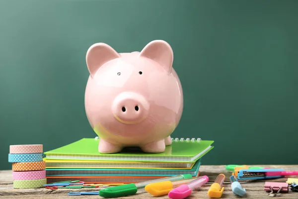 Pink piggy bank with school supplies and notebooks — Stock Photo, Image
