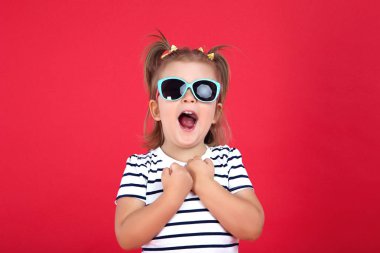 Kırmızı arka planda güneş gözlüğü sevimli küçük kız