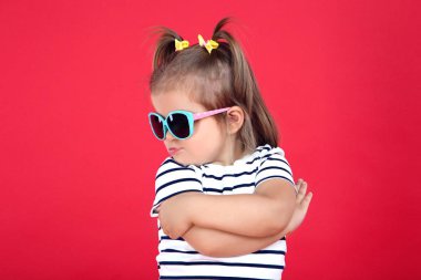Kırmızı arka planda güneş gözlüğü sevimli küçük kız