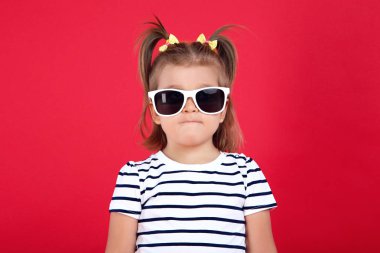 Kırmızı arka planda güneş gözlüğü sevimli küçük kız