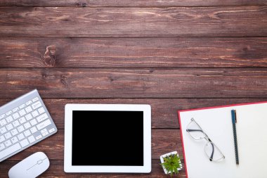 Kahverengi ağaçlık üzerinde ofis malzemeleri ile tablet ve bilgisayar klavyesi