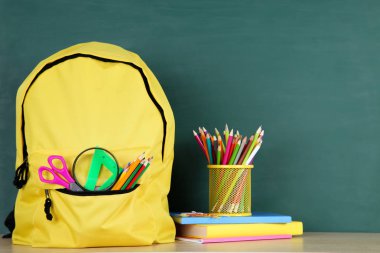 Tebeşir tahtası arka planda sarı sırt çantası ile Okul malzemeleri