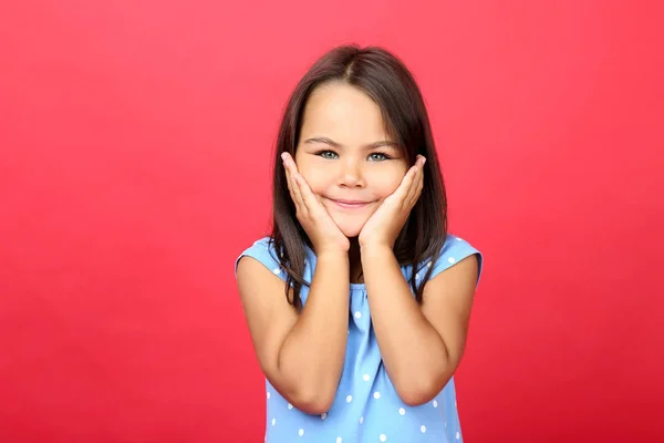 Красивая маленькая девочка в синем платье на красном фоне — стоковое фото