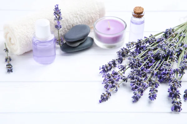 Lavender flowers with oil in bottles, candle and spa stones on w — Stock Photo, Image