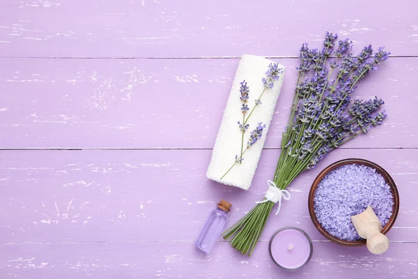 Lavender flowers with oil, salt and candle on puple wooden table — Stock Photo, Image
