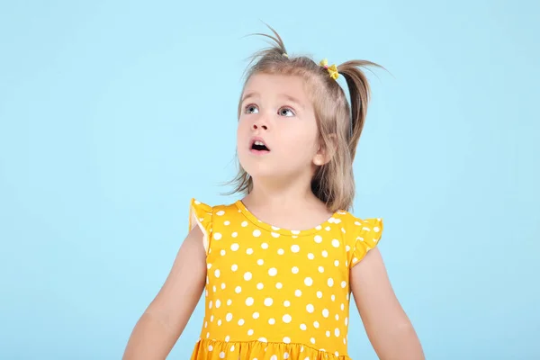 Söt liten flicka i gul klänning på blå bakgrund — Stockfoto