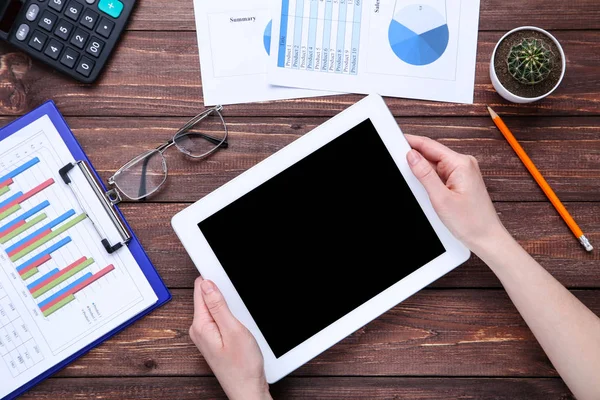Tablet bilgisayar ve ahşap masa üzerinde grafik ve grafikler ile kağıtları