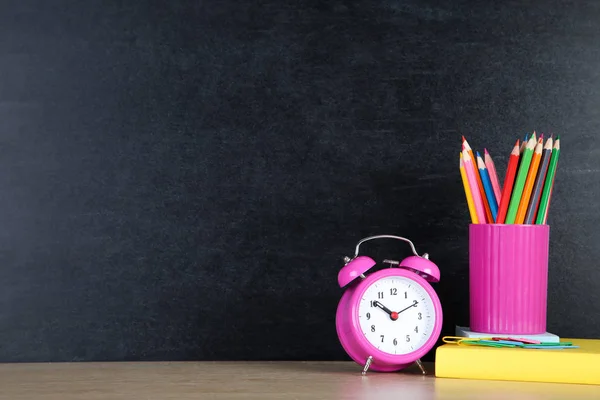 Material escolar con despertador rosa sobre fondo pizarra —  Fotos de Stock