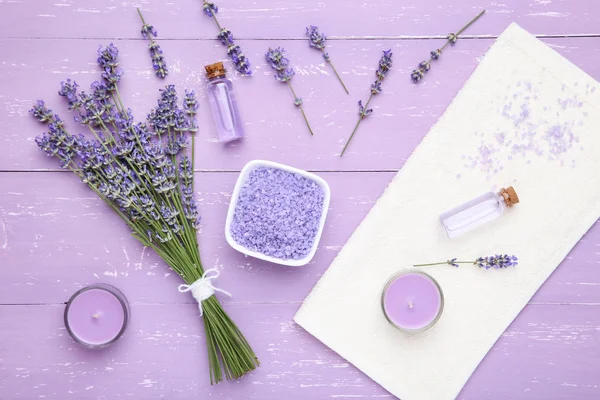 Lavender flowers with oil, salt and candle on puple wooden table — Stock Photo, Image