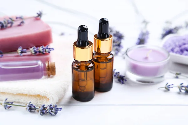 Lavender oil in bottles with flowers, candle and soap on white w — Stock Photo, Image