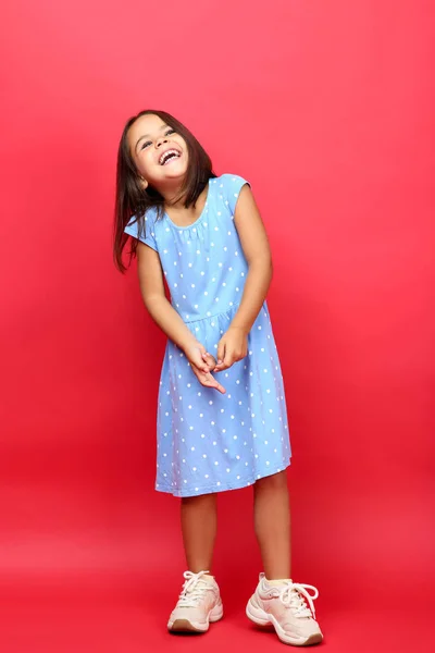 Menina bonita em vestido azul no fundo vermelho — Fotografia de Stock