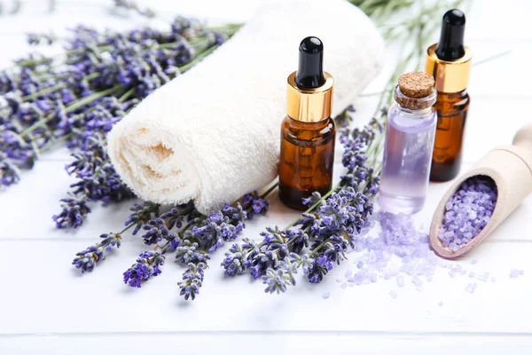 Lavender flowers with oil in bottles, salt and towel on white wo — Stock Photo, Image