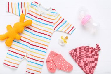 Beyaz arka planda yumuşak oyuncak ve emzitli bebek kıyafetleri