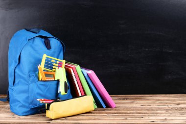 Siyah arka planda okul malzemeleriyle dolu sırt çantası.