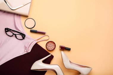 Bej arka planda kozmetik ile şık kadın giysileri