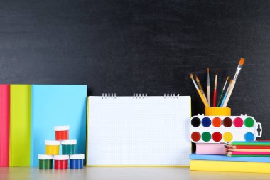 Kara tahta backgrou üzerinde kağıt boş levha ile Okul malzemeleri
