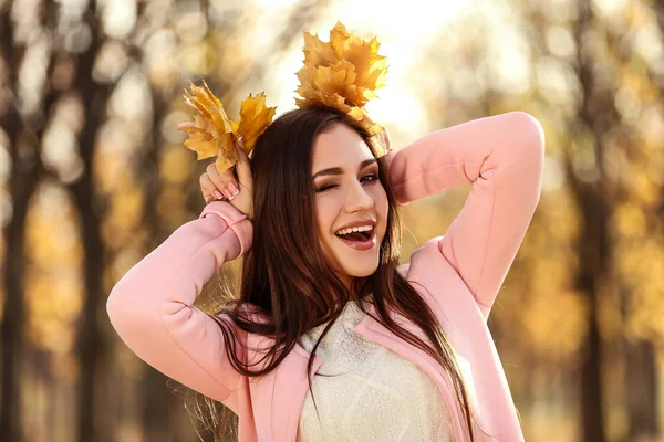 Beautiful woman with maple leafs in autumn park — Stock Photo, Image