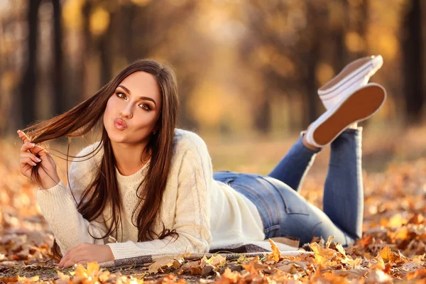 Mooie vrouw liggend op de grond in herfst park — Stockfoto