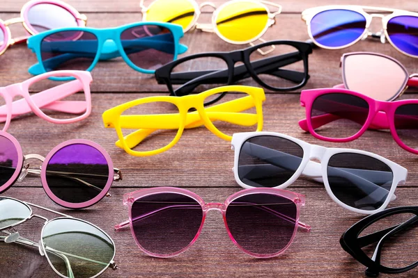 Sunglasses and eye glasses on brown wooden table — Stock Photo, Image