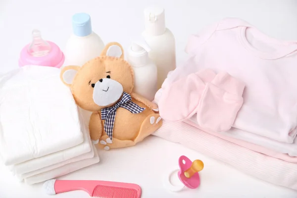 Folded clothes with diapers, baby supplies and soft bear toy — Stock Photo, Image