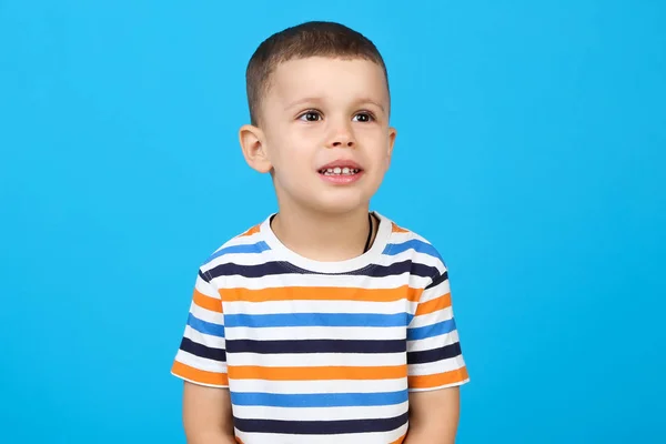 Söt liten pojke på blå bakgrund — Stockfoto