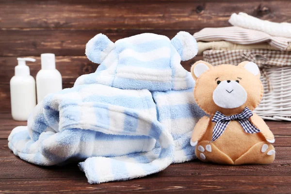 Baby clothes with soft bear toy on brown wooden table