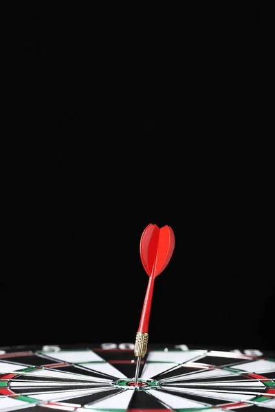 Dartboard com dardos no fundo preto — Fotografia de Stock