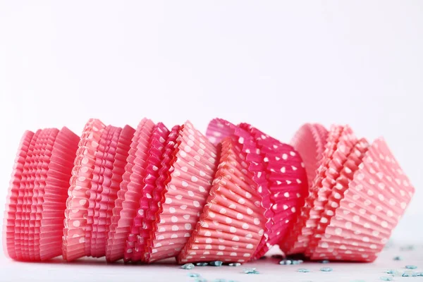 Pink cupcake cases on white wooden table — Stock Photo, Image