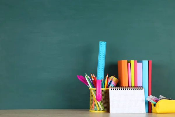 Schulbedarf mit schwarzem Blatt Papier auf grünem Hintergrund — Stockfoto